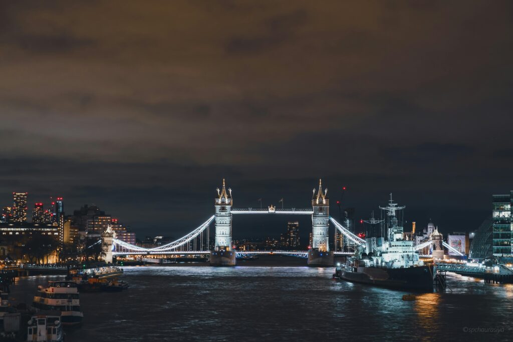 A view of the London Tower Bridge at night with city lights