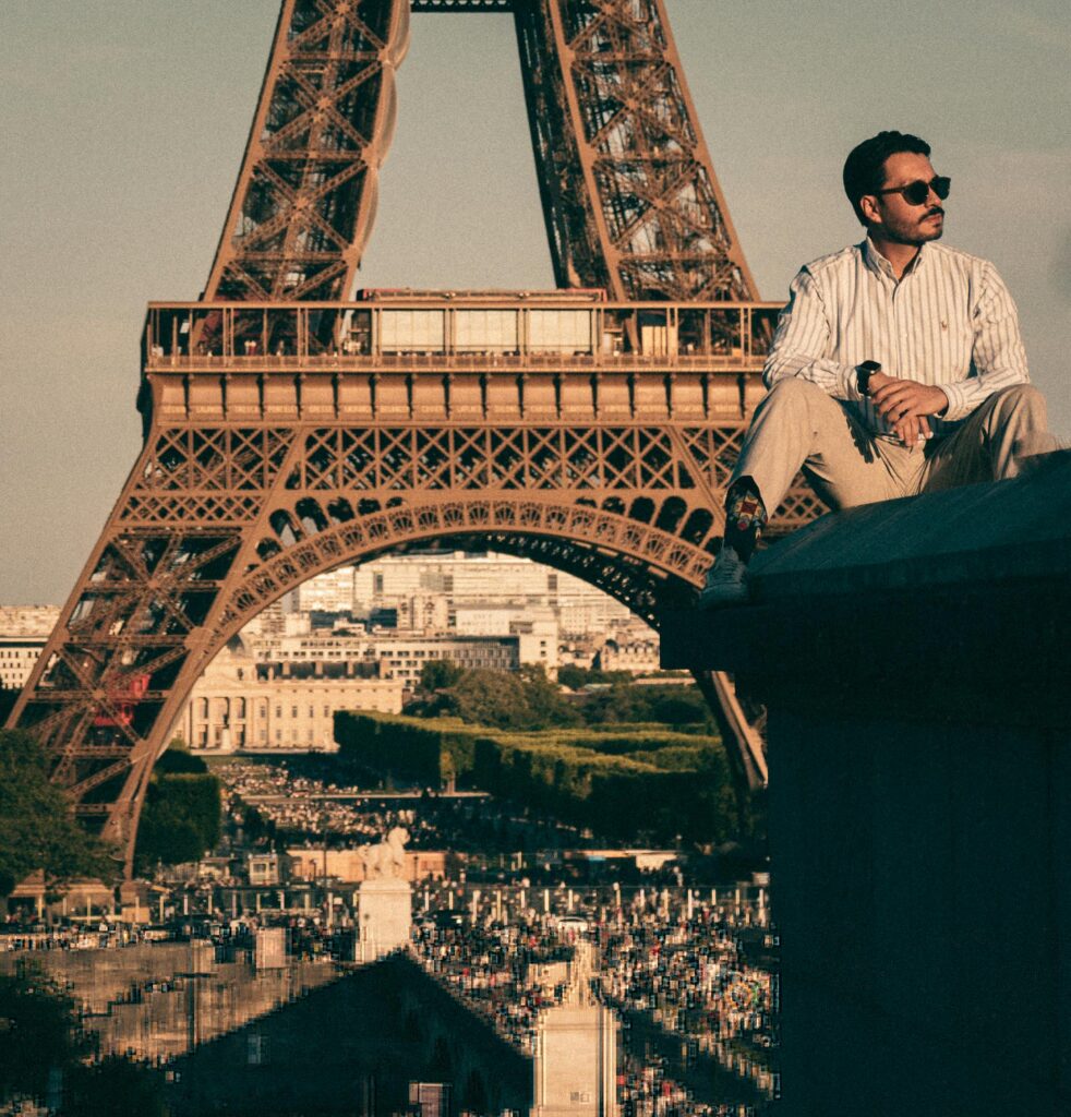 Casual scene of a young man with sunglasses in front of the Eiffel Tower, Paris travel experience.